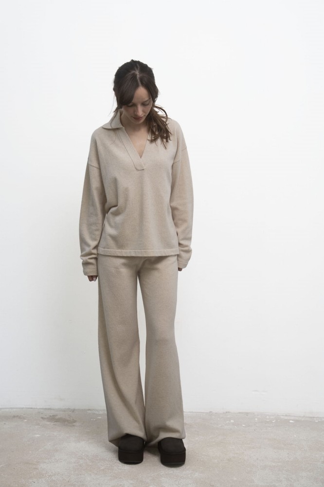 Spodnie Lorenza Beige – beżowe spodnie damskie, modelka w beżowym swetrze polo, ujęcie przodem ze wzrokiem skierowanym w dół