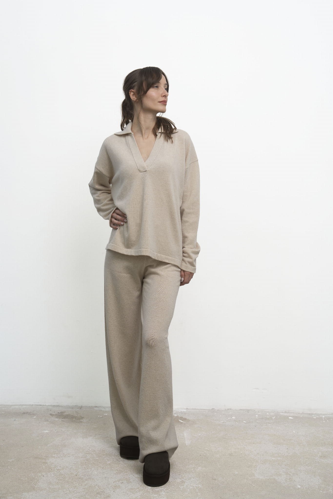 Sweter Lorenza Beige – beżowy sweter damski, przodem, modelka odwraca głowę w bok, beżowe spodnie