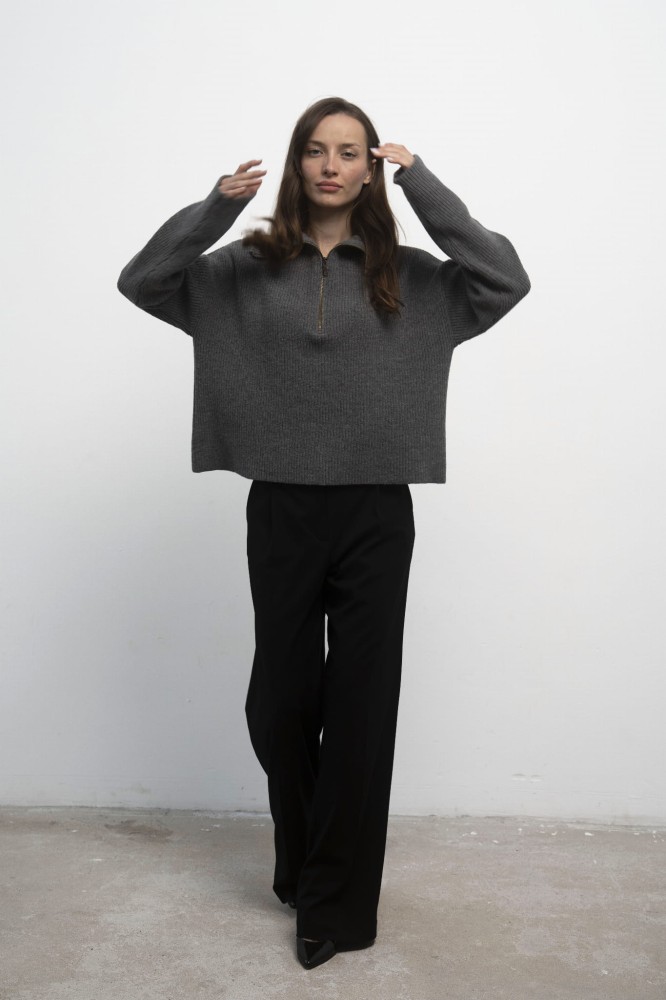 Sweter Luna Grey – szary sweter damski, przodem, ręce uniesione w górę, czarne spodnie