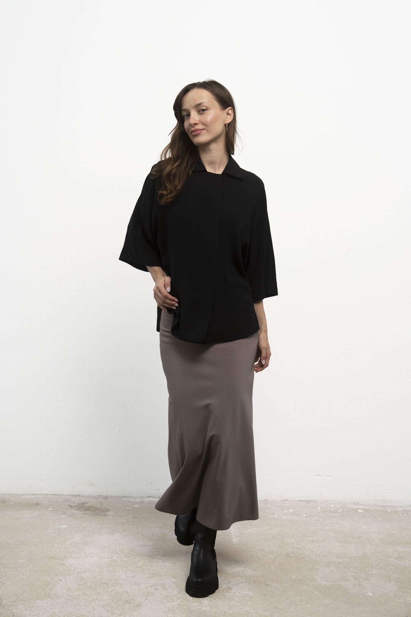 Spódnica Grace Beige midi, czarna koszula, ujęcie przodem, modelka w lekkim ruchu.