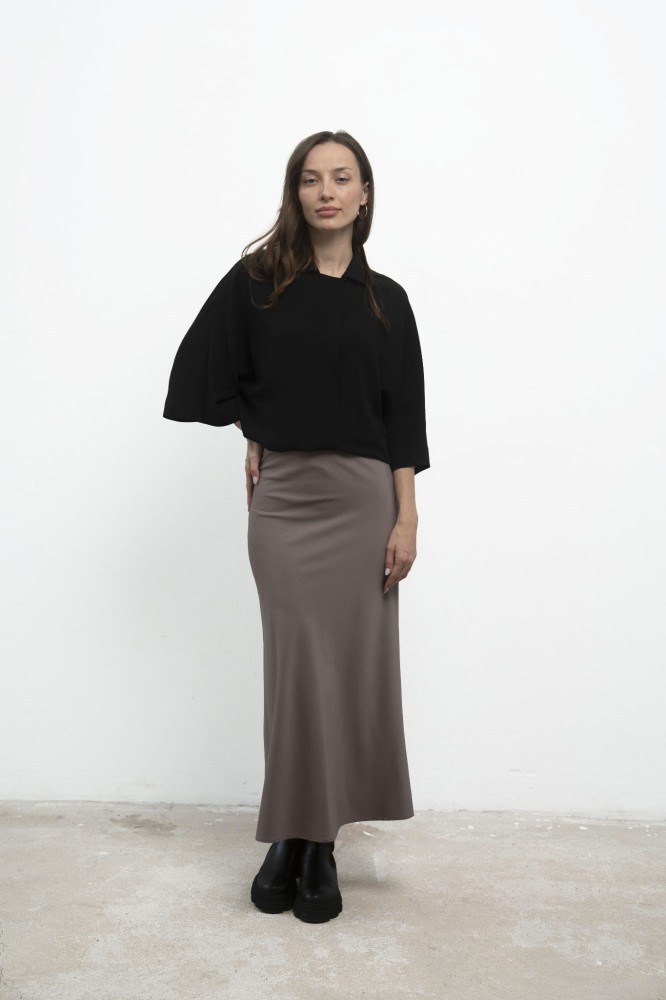 Spódnica Grace Beige, stylizacja z czarną koszulą, ujęcie przodem z ręką na biodrze.